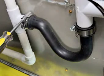 Tightening the clamp on the condensate trap with a screwdriver
