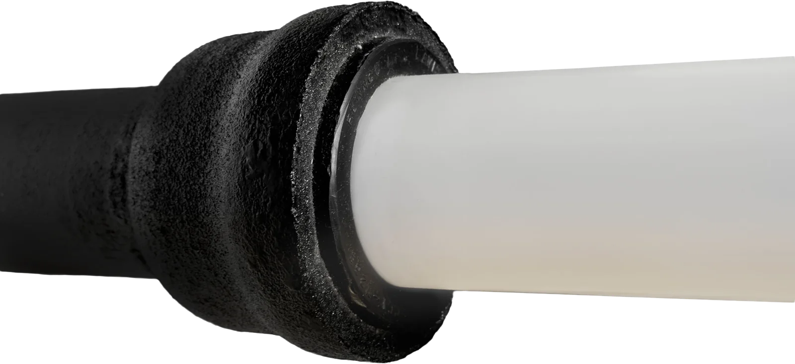 White PVC pipe sealed into a black cast iron hub with a Fernco Donut