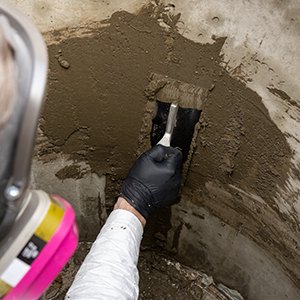 Troweling QSR repair mortar onto a manhole wall