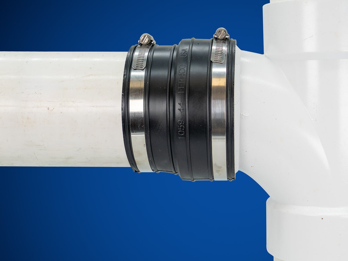 Fernco 1059-44 socket coupling joining 4 inch PVC pipe to the hub of a PVC sanitary tee
